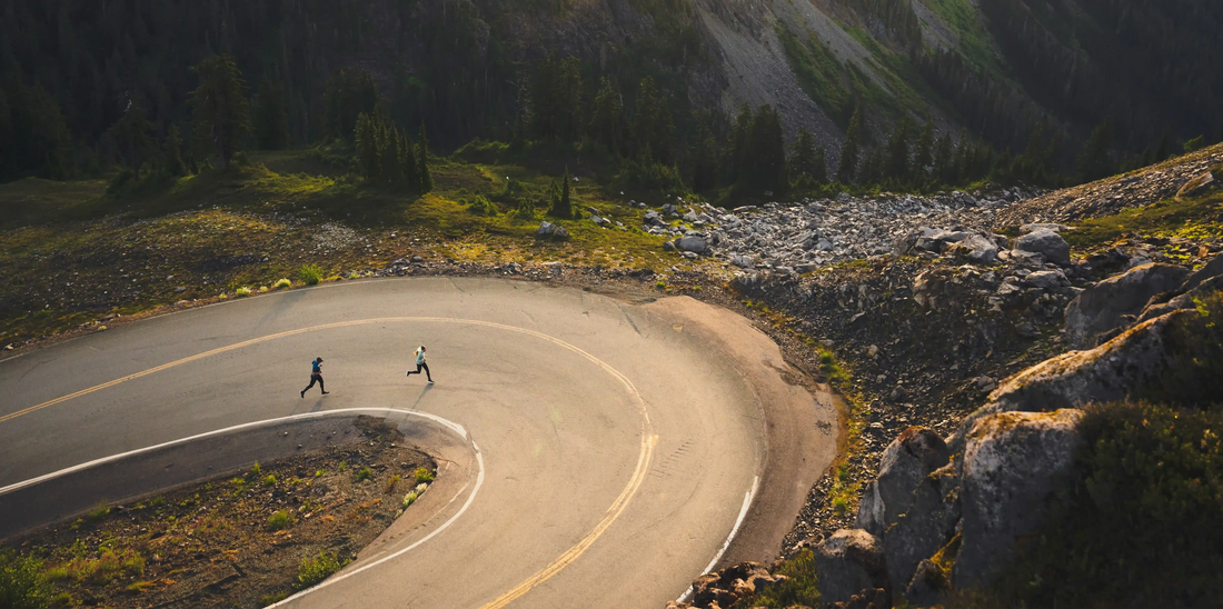 People on paved road running up a hill surrounded by mountainous terrain