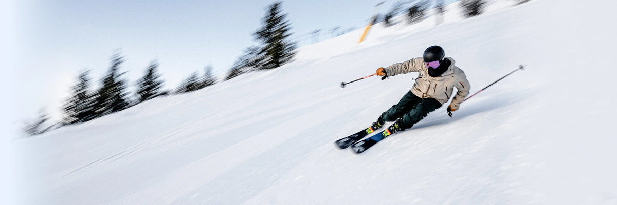 Person skiing down a snowy slope with ski poles and a helmet.