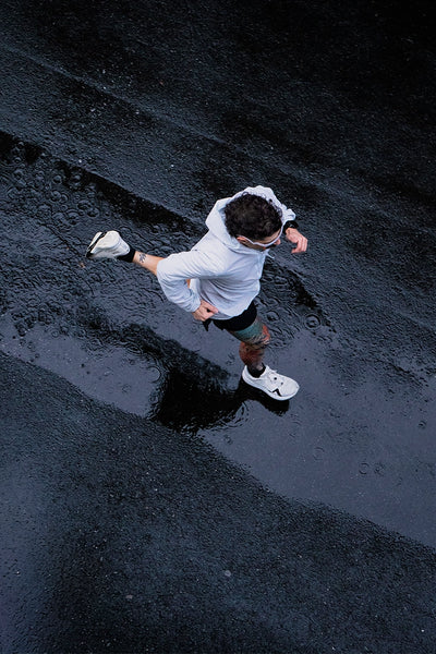 Birds eye view of a man running on wet pavement in the rain. 