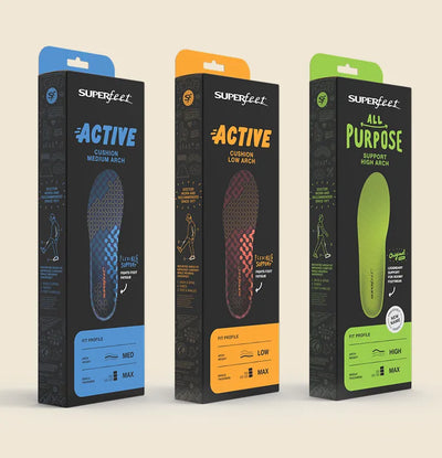 Three Superfeet insole packaging boxes on a beige background