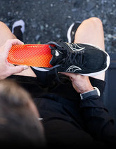 Person holding an athletic shoe inserting a Superfeet insole.