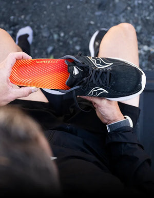 Person holding an athletic shoe inserting a Superfeet insole.